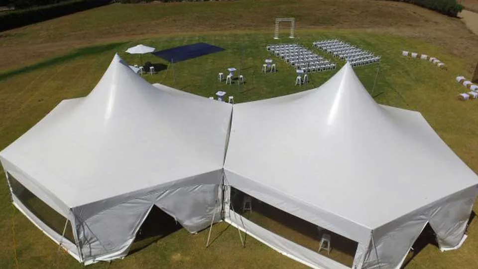 Two marquees linked along one wall, seen from above, with chairs set out in rows on the grass beyond