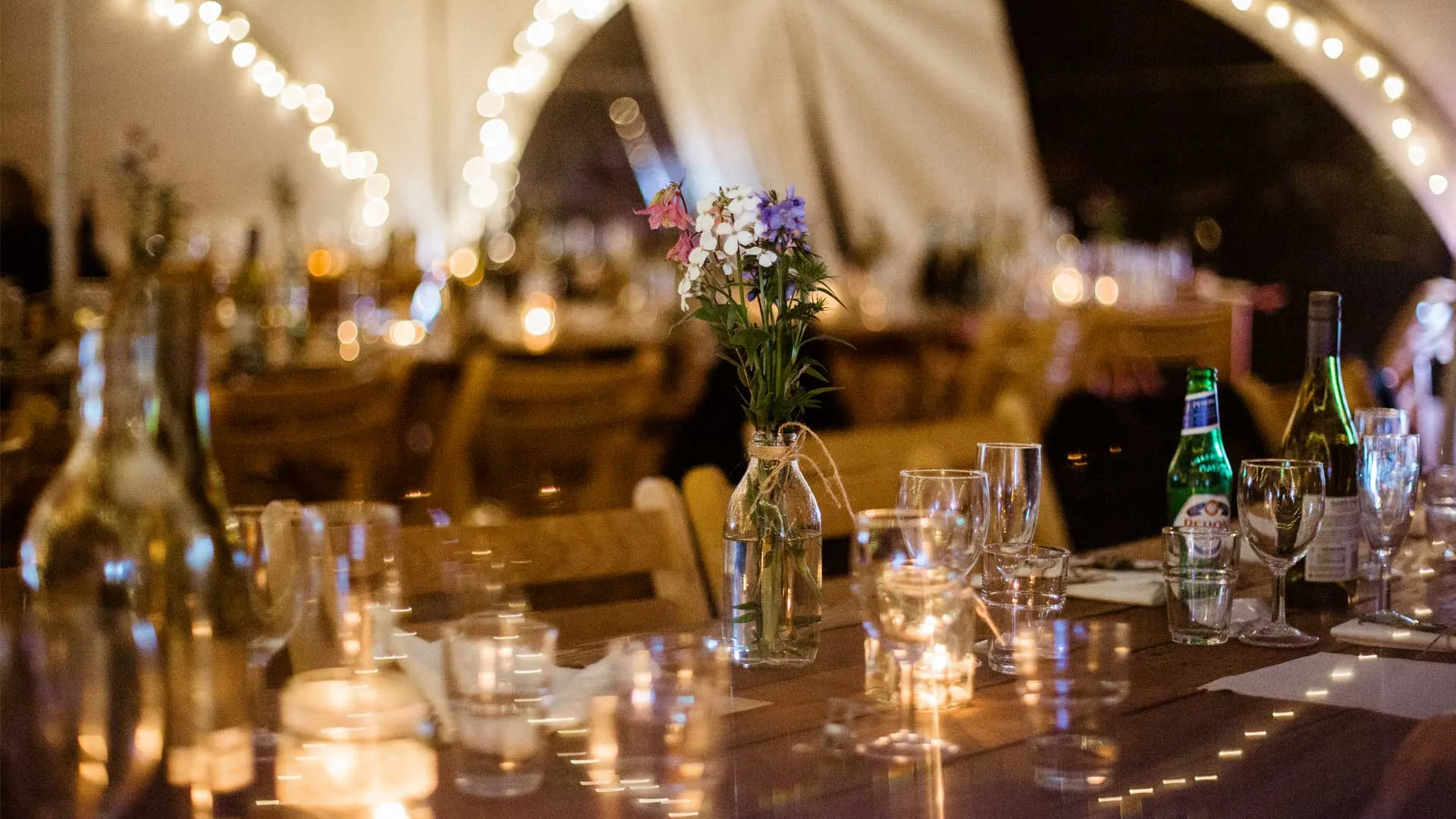 Wedding table inside a marquee, lit with fairy lights and candles